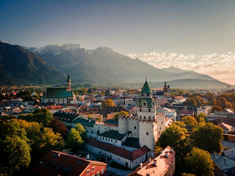 Altstadt von Hall in Tirol mit Münzerturm und Pfarrkirche im Abendlicht, dahinter Berge