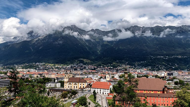 Blick über Innsbruck mit der Basilika Wilten, dahinter die Nordkette unter Wolken